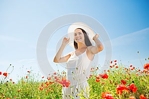 Smiling young woman in straw hat on poppy field