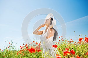 Smiling young woman in straw hat on poppy field