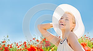 Smiling young woman in straw hat on poppy field