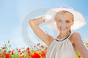 Smiling young woman in straw hat on poppy field