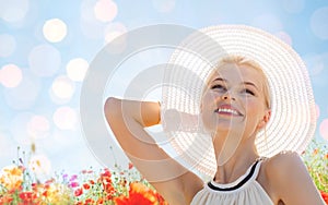 Smiling young woman in straw hat on poppy field