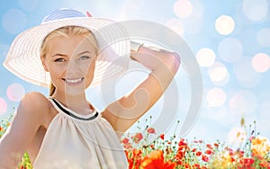 Smiling young woman in straw hat on poppy field