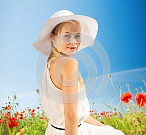 Smiling young woman in straw hat on poppy field