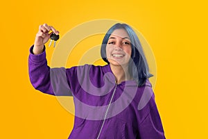 Smiling young woman student with blue hair holds a credit card and key