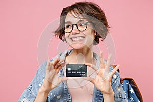 Smiling young woman student in denim clothes eyeglasses backpack posing isolated on pastel pink background. Education in