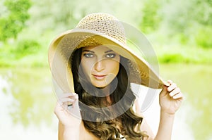 Smiling young woman in sun hat against background of summer green park. Beautiful healthy happy girl enjoying freedom