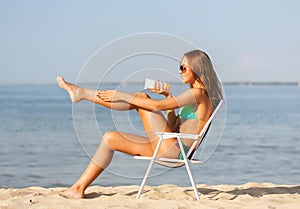 Smiling young woman sunbathing in lounge on beach