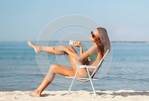 Smiling young woman sunbathing in lounge on beach