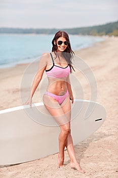 Smiling young woman with surfboard on beach