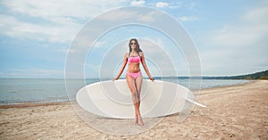 Smiling young woman with surfboard on beach