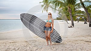 Smiling young woman with surfboard on summer beach
