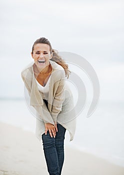 Smiling young woman in sweater having fun time on lonely beach