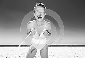 Smiling young woman in swimsuit on seacoast dressing swimsuit