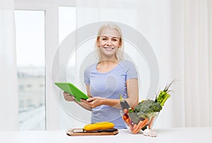 Smiling young woman with tablet pc cooking at home