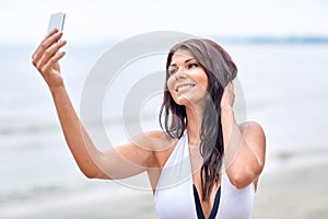 Smiling young woman taking selfie with smartphone