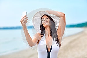 Smiling young woman taking selfie with smartphone