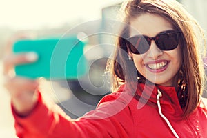 Smiling young woman taking selfie with smartphone