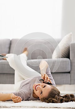 Smiling young woman talking mobile phone while laying on floor