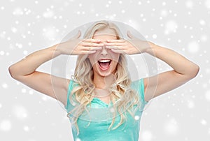Smiling young woman or teen girl covering her eyes