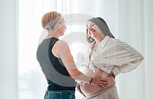 Smiling young woman tender touching partner's female pregnant belly. Same-sex marriage couple . Woman'