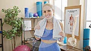 Smiling young woman with a towel in a gym, displaying fitness, wellbeing, and active lifestyle photo