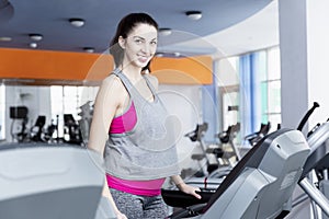 Smiling young woman on a treadmill in the gym. Active lifestyle and health