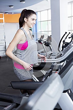 Smiling young woman on a treadmill in the gym. Active lifestyle and health. Vertical