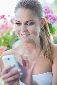 Smiling young woman typing an sms on her mobile