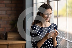 Smiling young woman use smartphone texting online