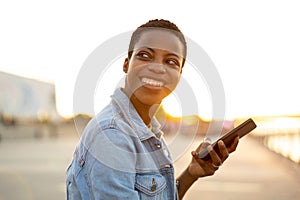 Smiling young woman using smartphone outdoors