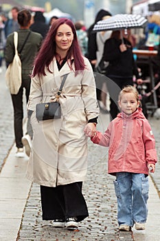 Smiling young woman walking with her little daughter.