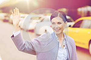 Smiling young woman with waving hand over taxi