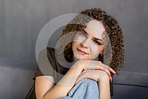 Smiling young woman wearing casual clothes relaxing on a couch at home