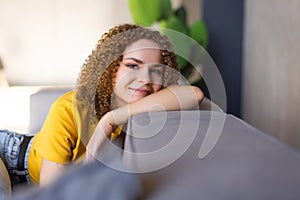 Smiling young woman wearing casual clothes relaxing on a couch at home