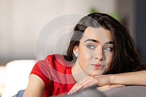 Smiling pretty young woman wearing casual clothes relaxing on a couch at home