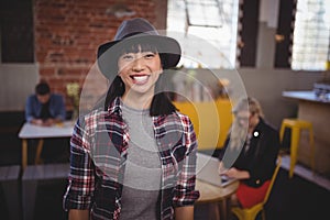 Smiling young woman wearing hat standing at coffee shop