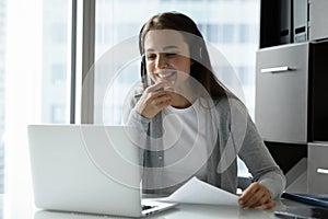 Smiling young woman wearing headset looking at laptop screen