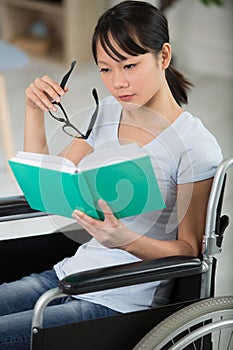 smiling young woman in wheelchair reading book