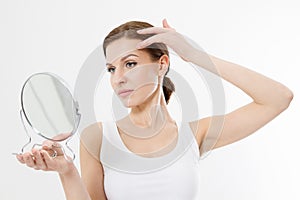 Smiling young woman with white teeth looking in mirror isolated on white background. Skin care and anti aging concept. Beauty