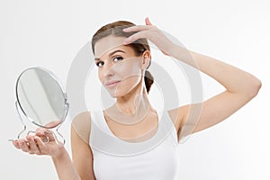 Smiling young woman with white teeth looking in mirror isolated on white background. Skin care and anti aging concept. Beauty