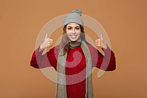 Smiling young woman in winter clothes showing thumbs up gesture