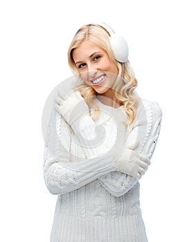 Smiling young woman in winter earmuffs and sweater