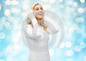 Smiling young woman in winter earmuffs and sweater