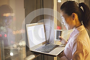 Smiling young woman working in the office on her laptop at night