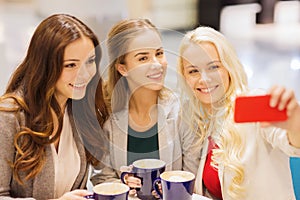 Smiling young women with cups and smartphone