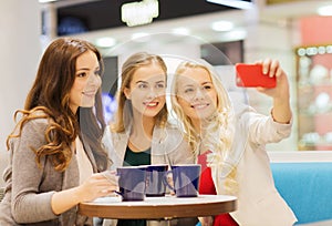 Smiling young women with cups and smartphone