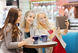 Smiling young women with cups and tablet pc