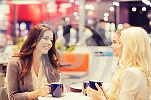 Smiling young women drinking coffee in mall