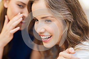 Smiling young women gossiping and whispering