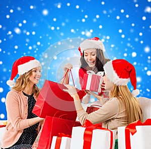 Smiling young women in santa hats with gifts